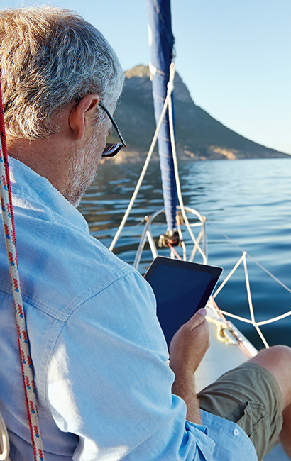 Retired man reading tablet on sailboat