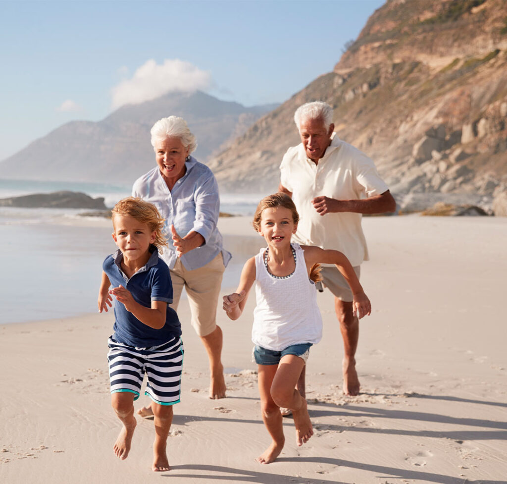grandparents running on the beach with their grandchildren