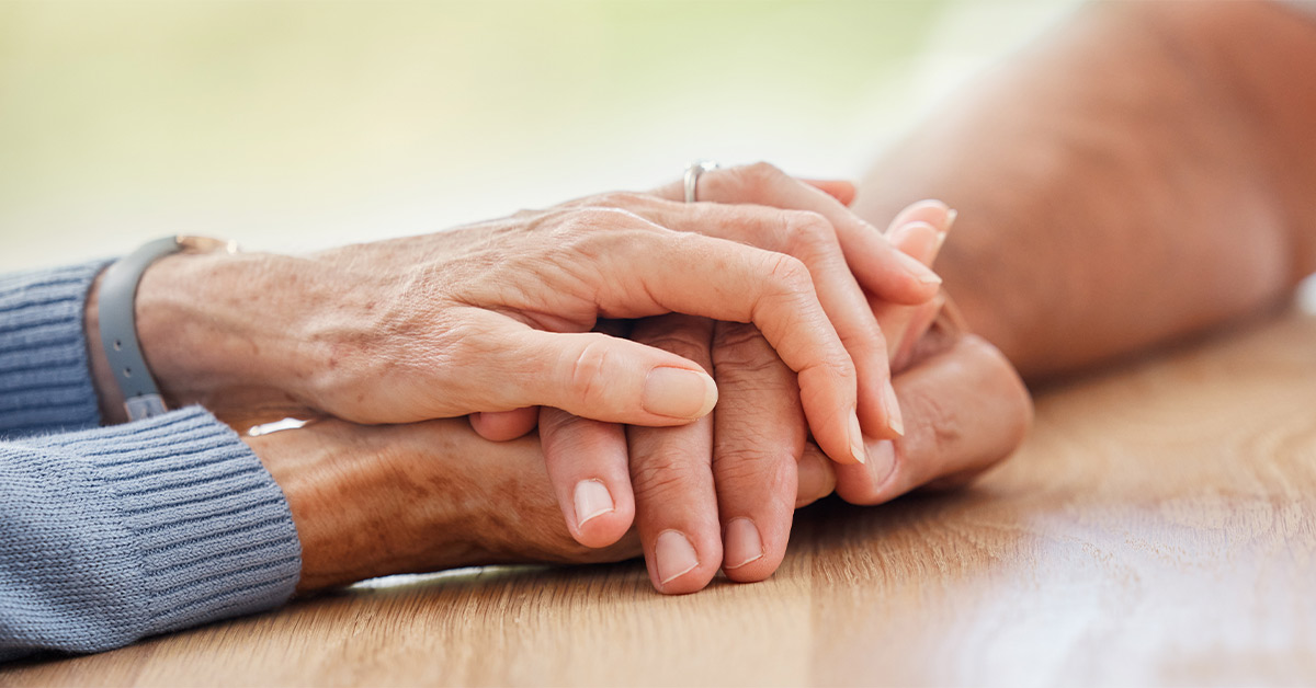 elderly person holding hands with another prolonged grief disorder
